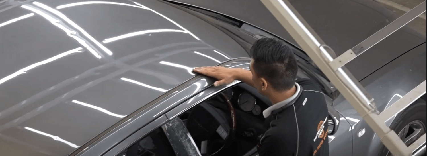 Hail repairer network banner - car being assessed by a technician under a light tunnel to locate all damage